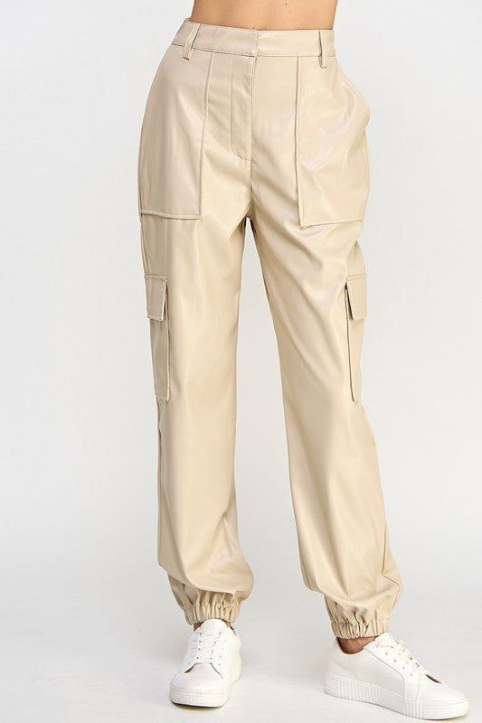 Beige cargo pants worn with white sneakers on a light gray background