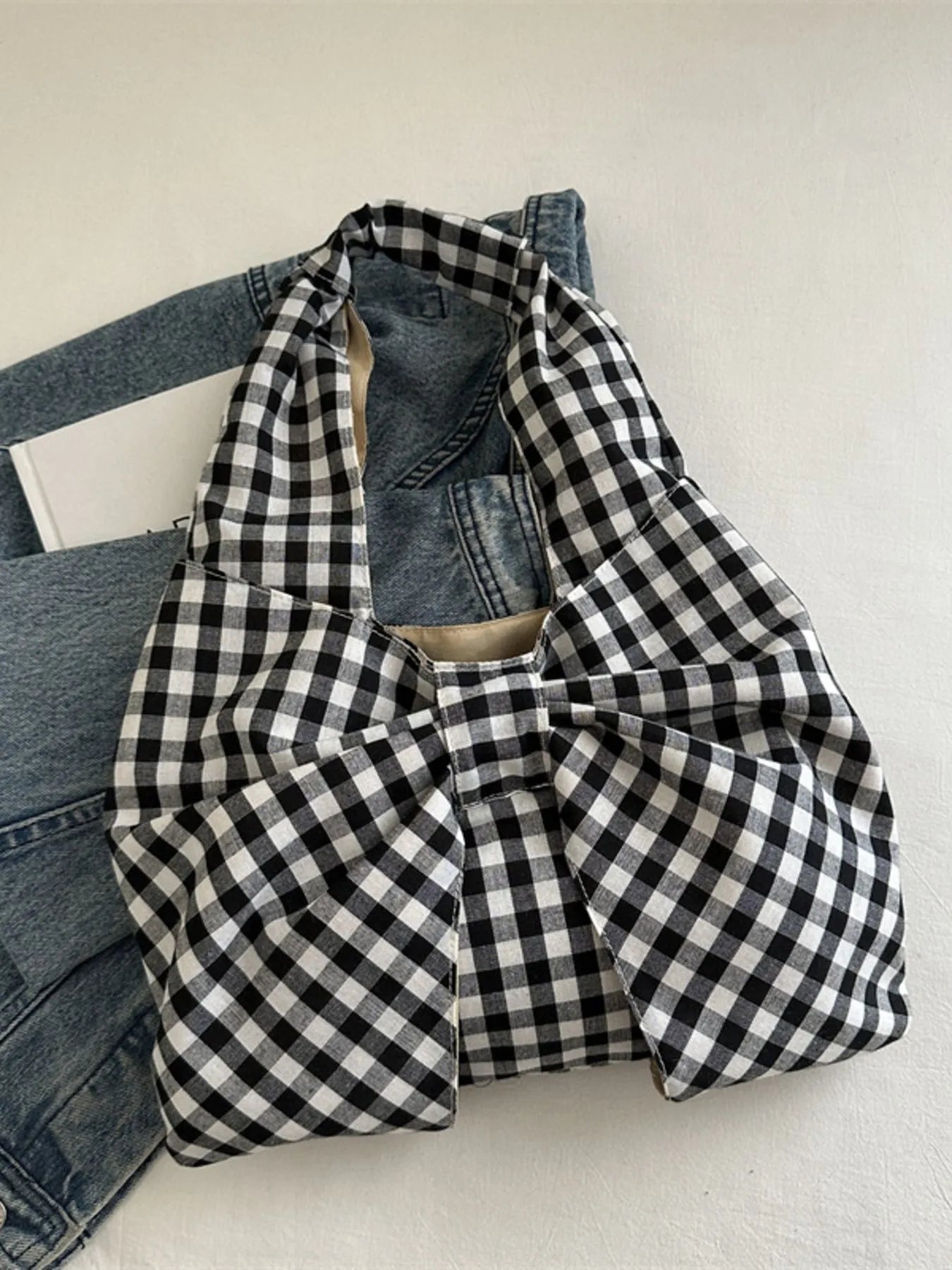 Black and white checkered shirt over denim jeans on a light background
