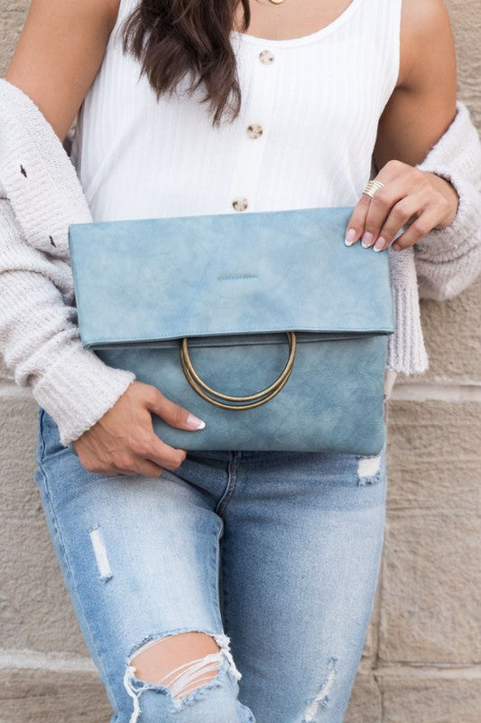 Person holding a blue clutch bag against a neutral background