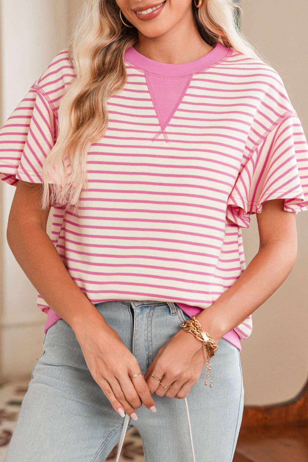 Woman wearing a pink and white striped shirt with a blurred background