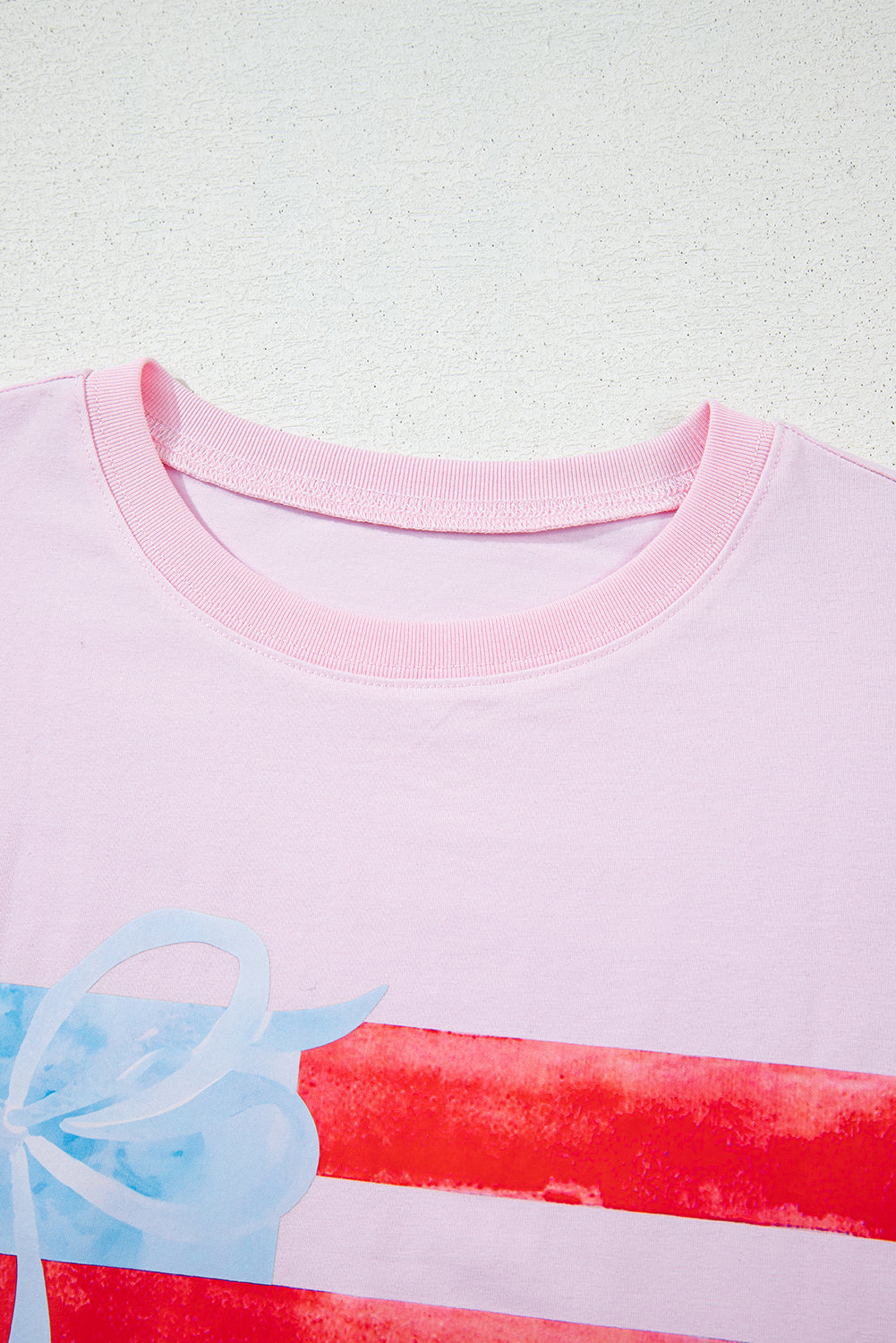 Close-up of a pink shirt with a colorful design on a light green background