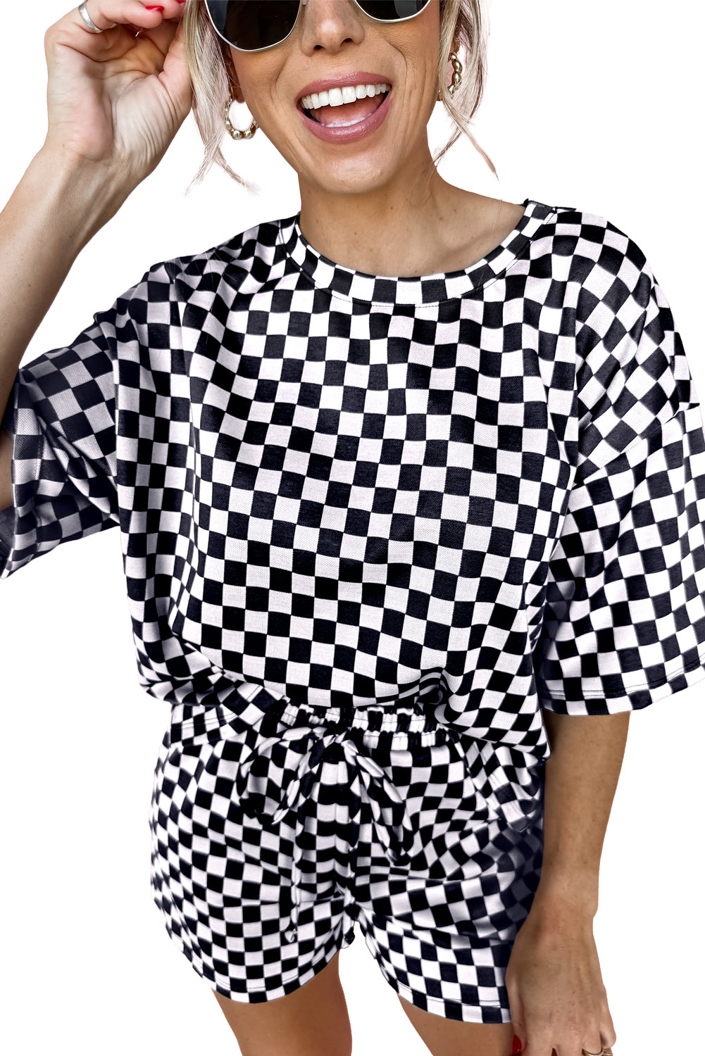 Person wearing a black and white checkered outfit with sunglasses on a white background