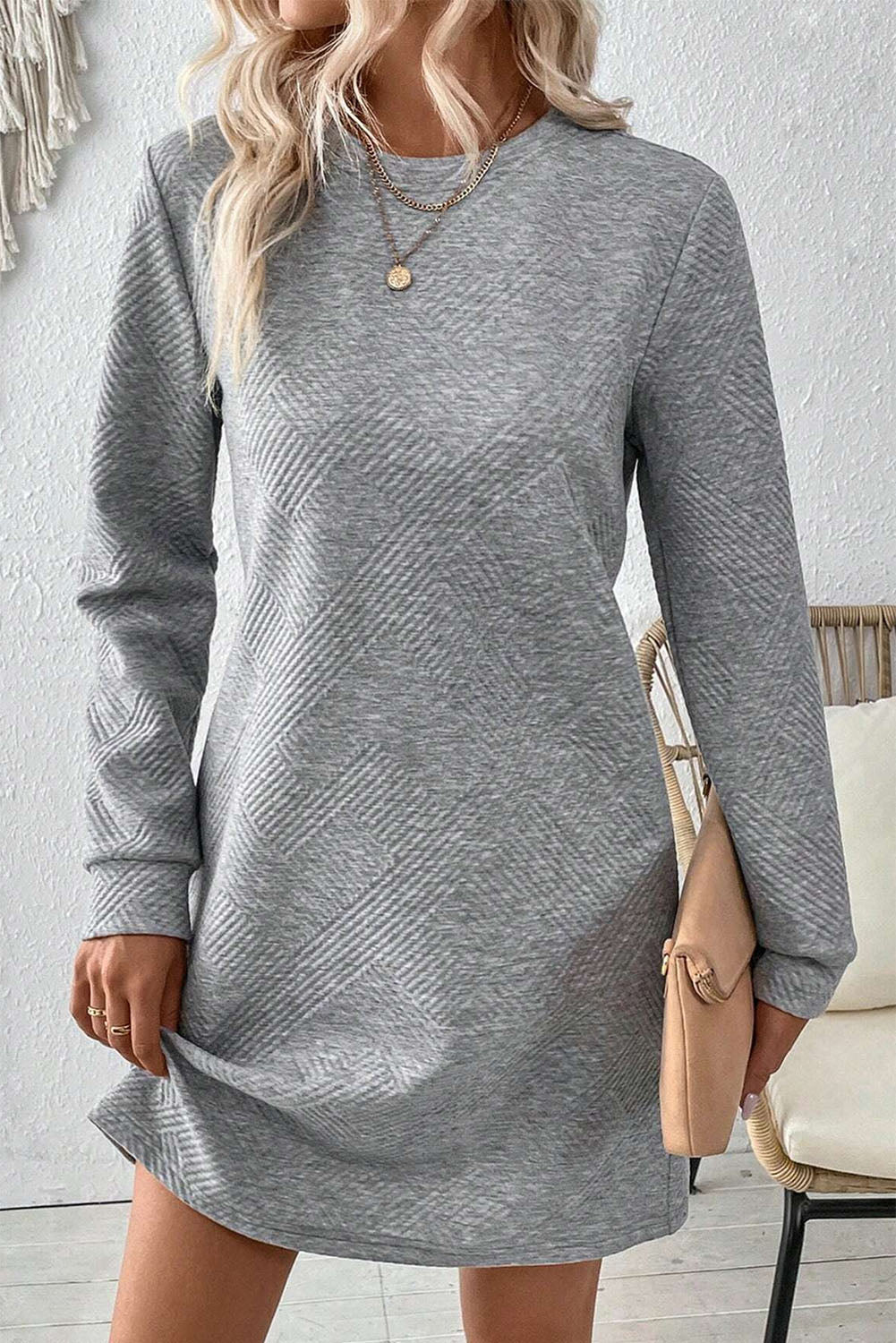 Woman wearing a gray long-sleeve dress with a white background