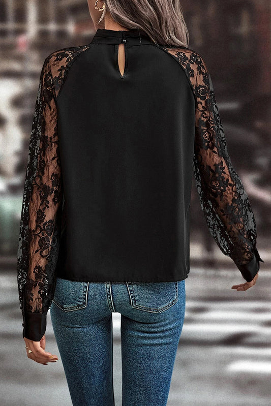 Black blouse with sheer lace sleeves worn by a person, blurred background