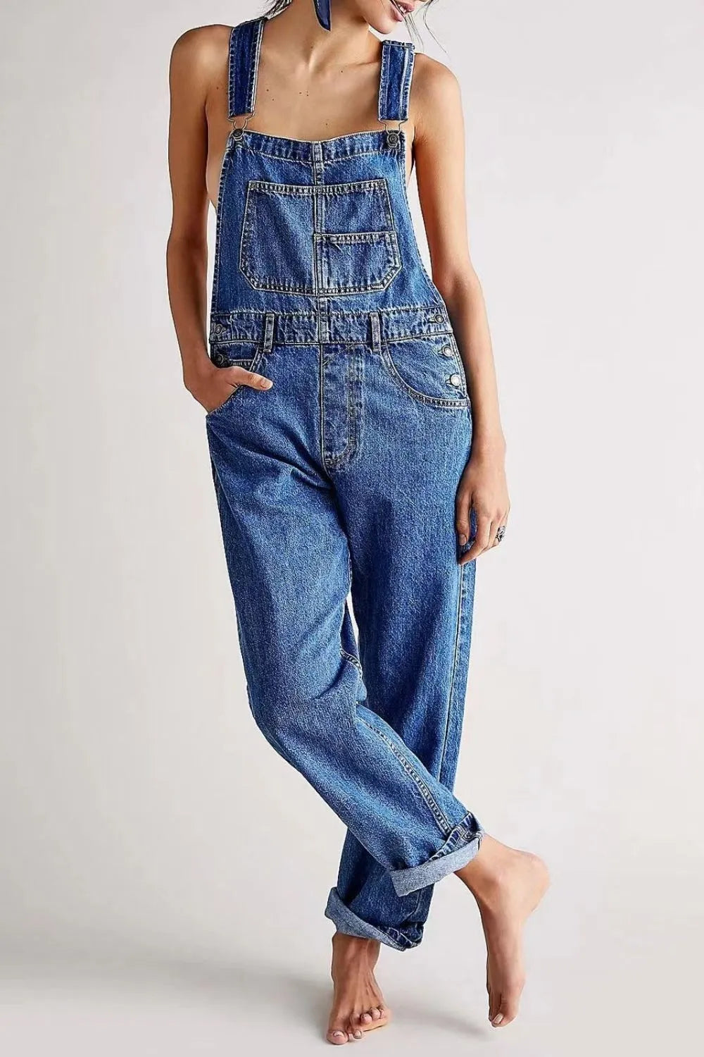 Person wearing blue denim overalls on a plain background