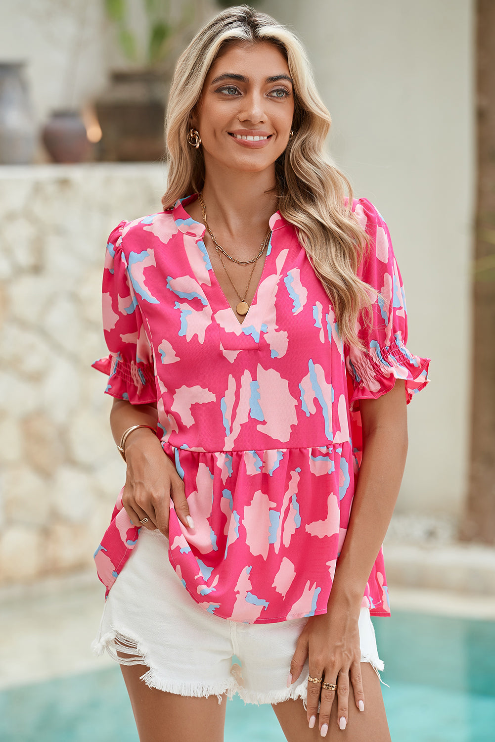 Woman wearing a pink floral blouse by a poolside