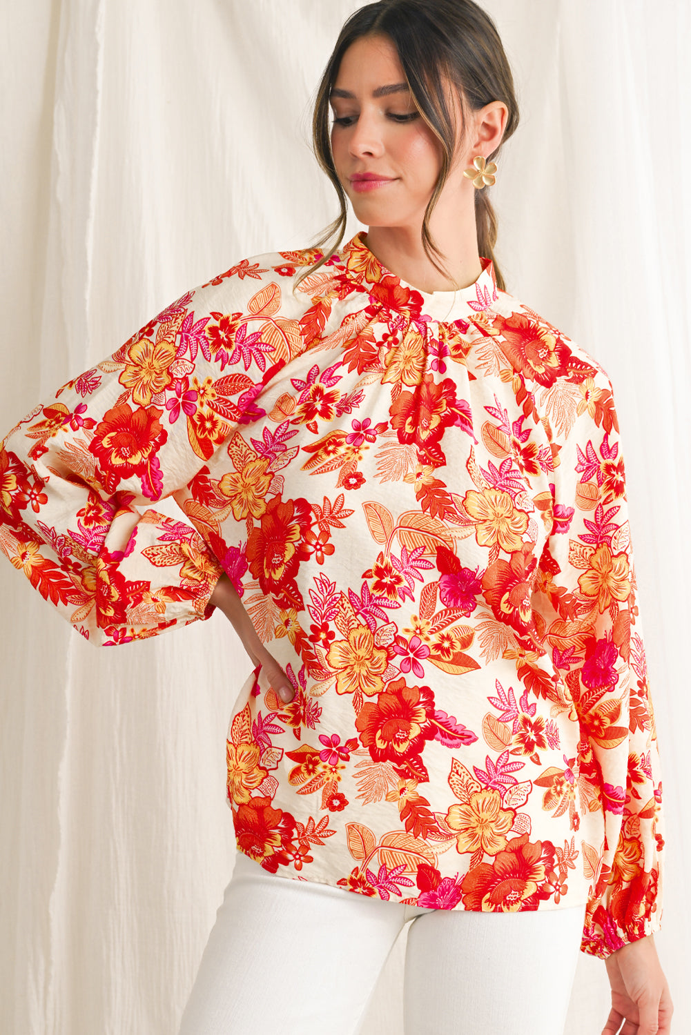 Woman wearing a colorful floral blouse against a white background