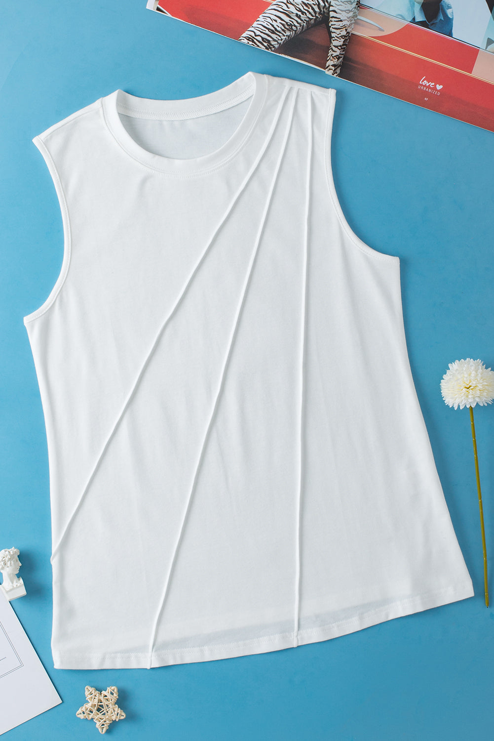 White sleeveless top on a blue background with decorative elements.