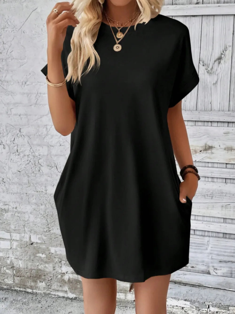 Person wearing a black dress against a textured wall background