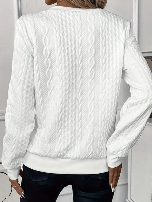 White cable knit sweater worn by a person, with a neutral background