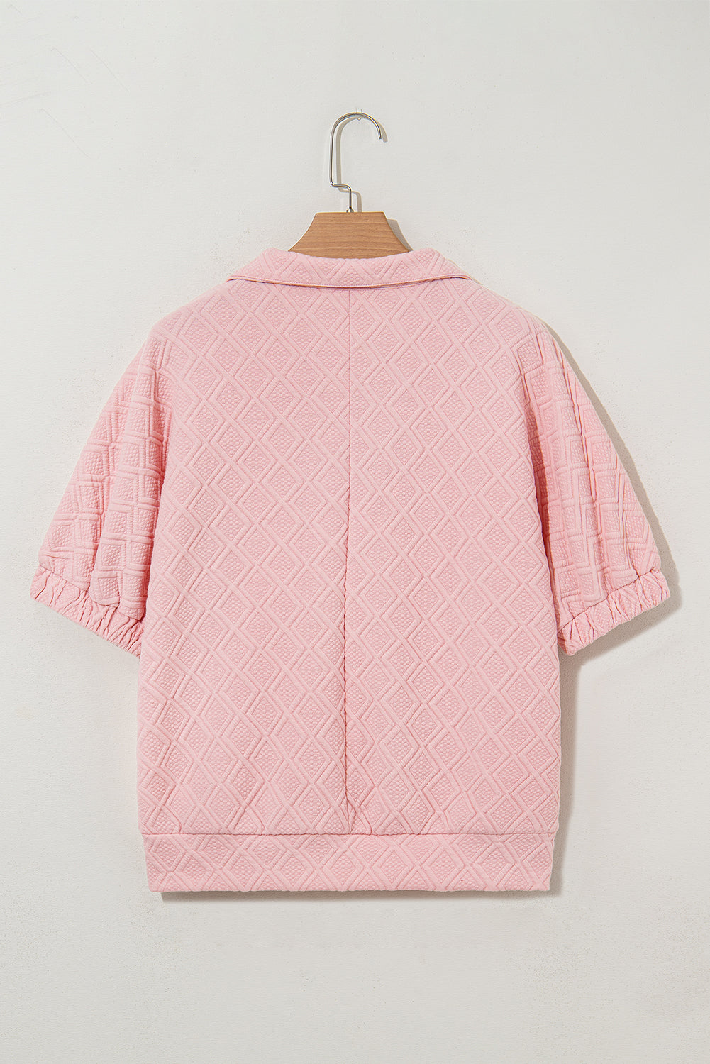 Pink quilted jacket on a hanger against a light gray background