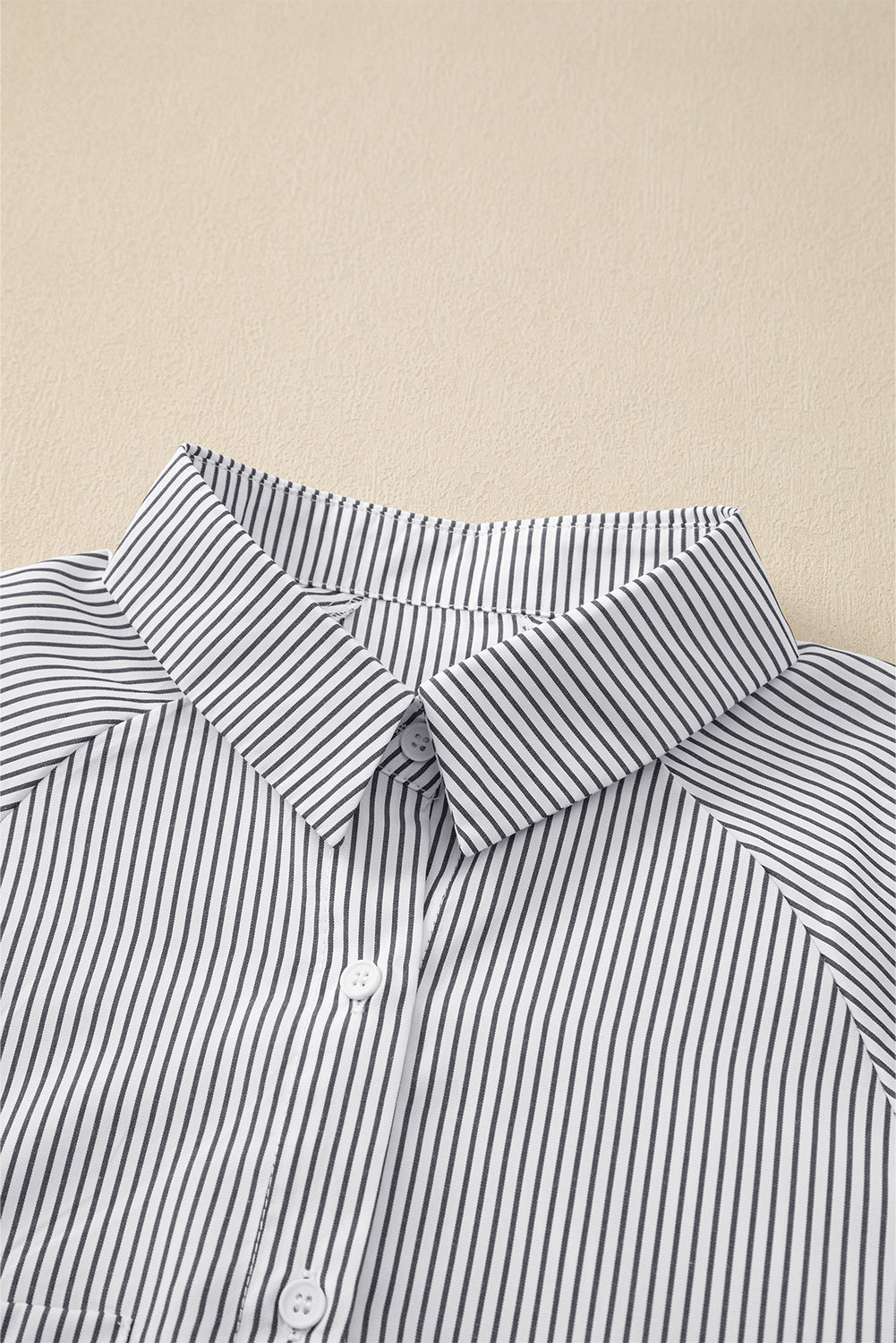Close-up of a striped shirt collar on a beige fabric background