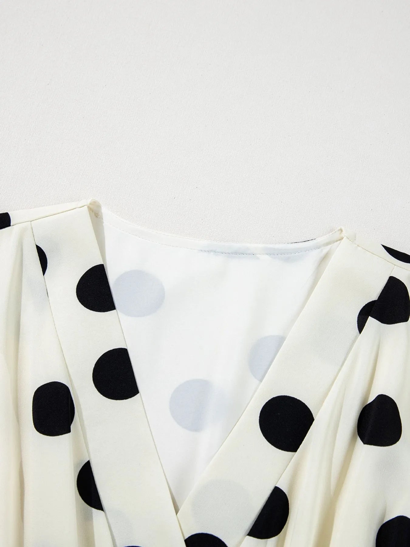 White fabric with black polka dots on a light gray background
