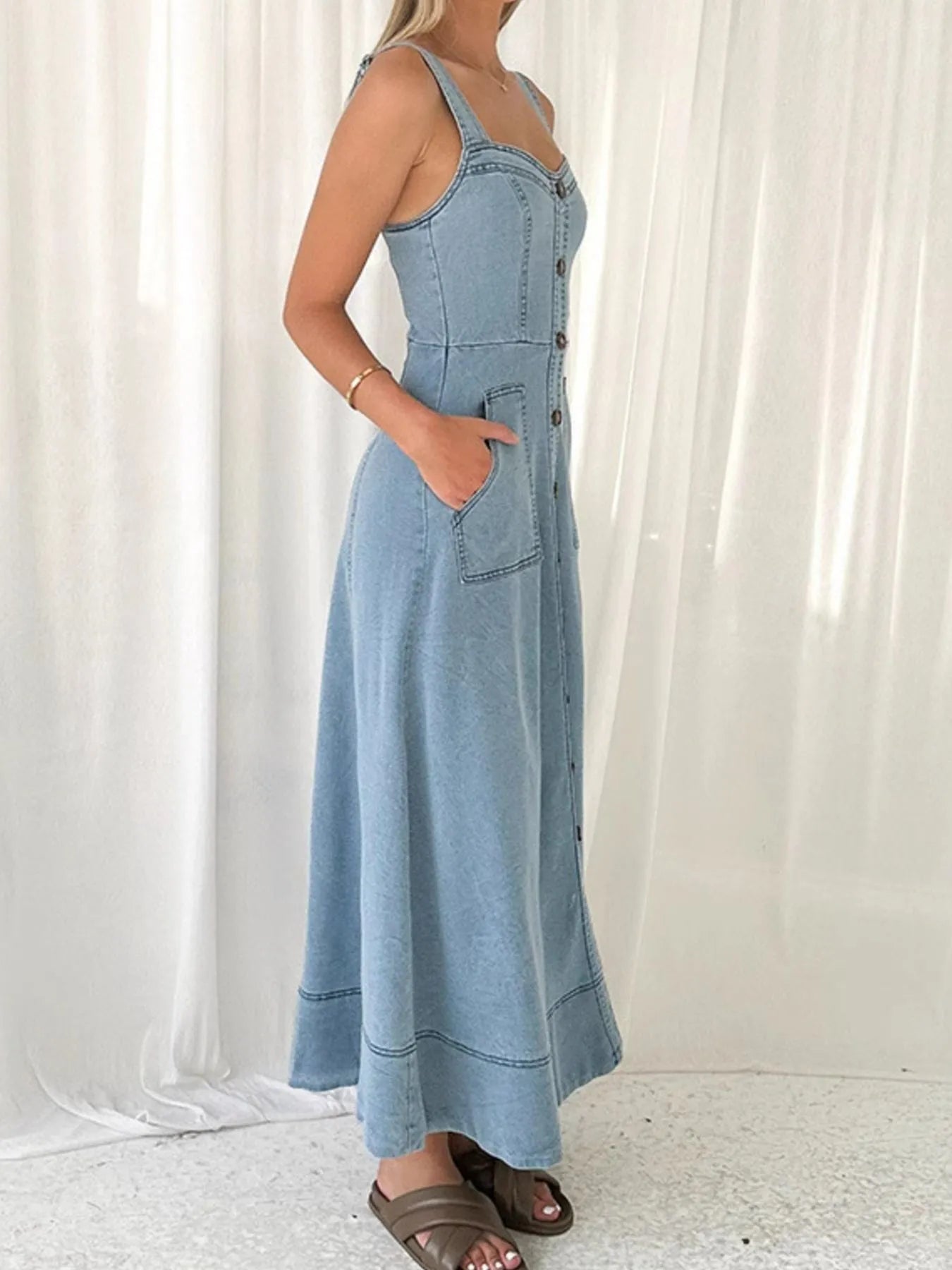 Woman wearing a blue denim dress against a white curtain background
