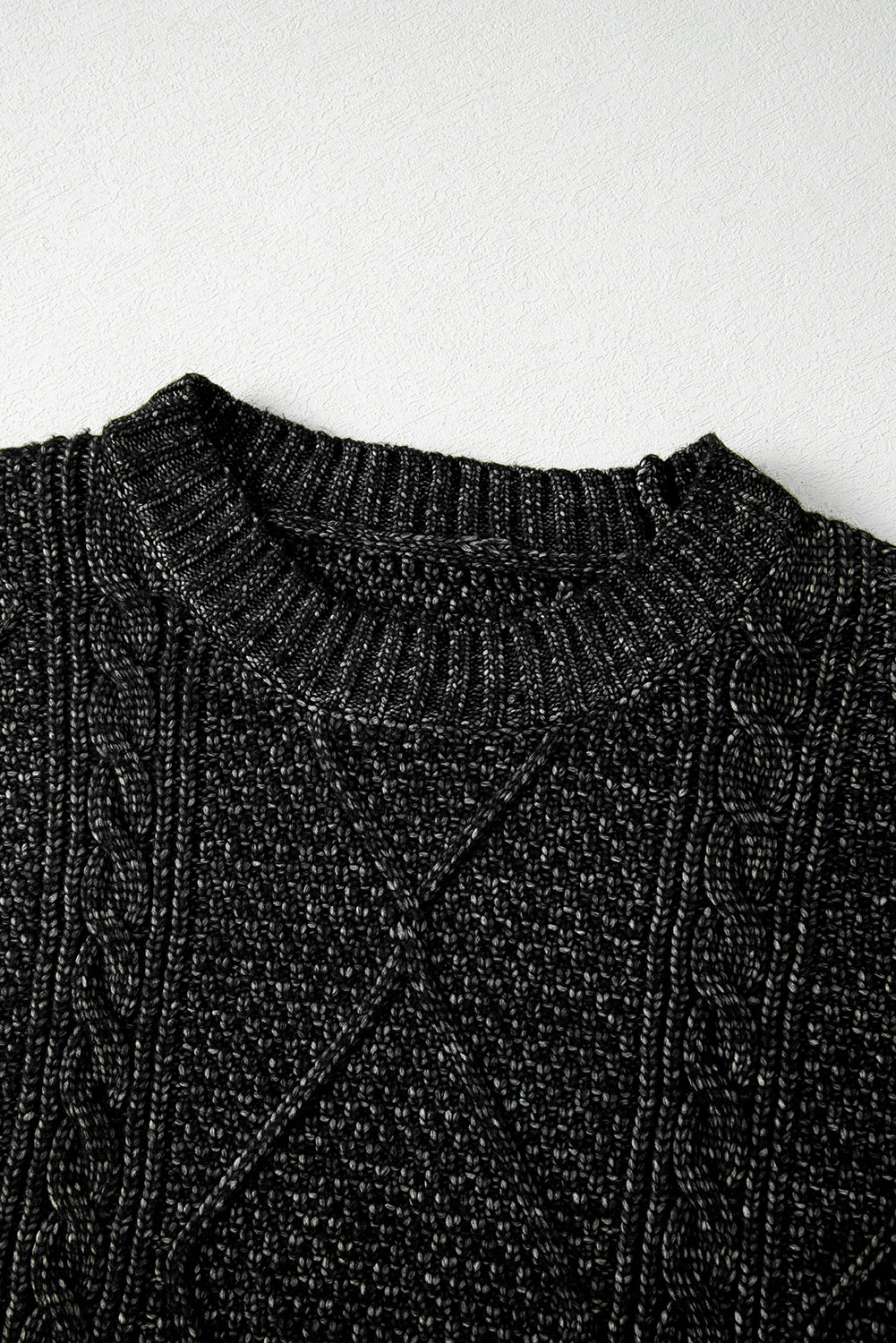 Close-up of a black knit sweater on a white background