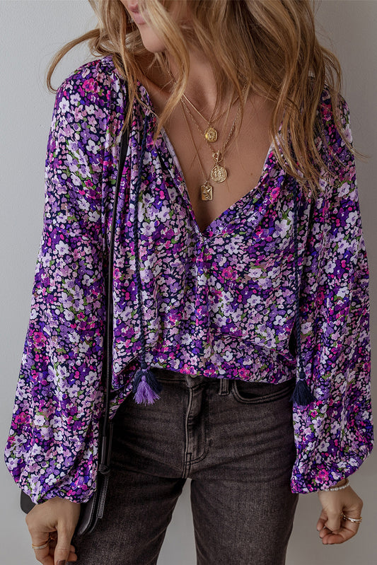 Person wearing a purple floral blouse with long sleeves and dark jeans.
