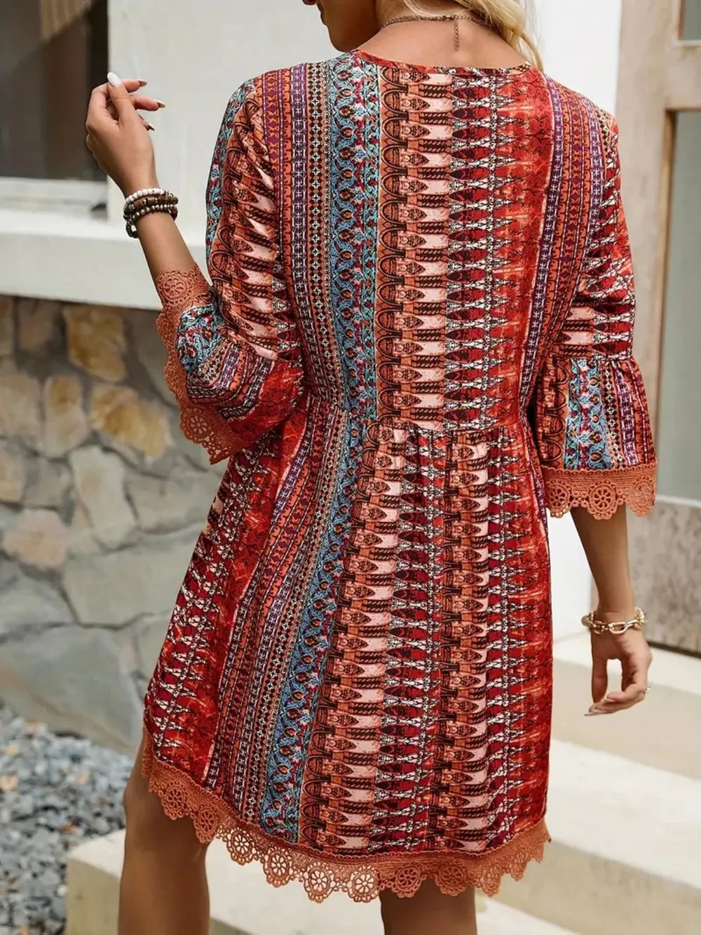 Woman wearing a colorful patterned dress with a stone wall background
