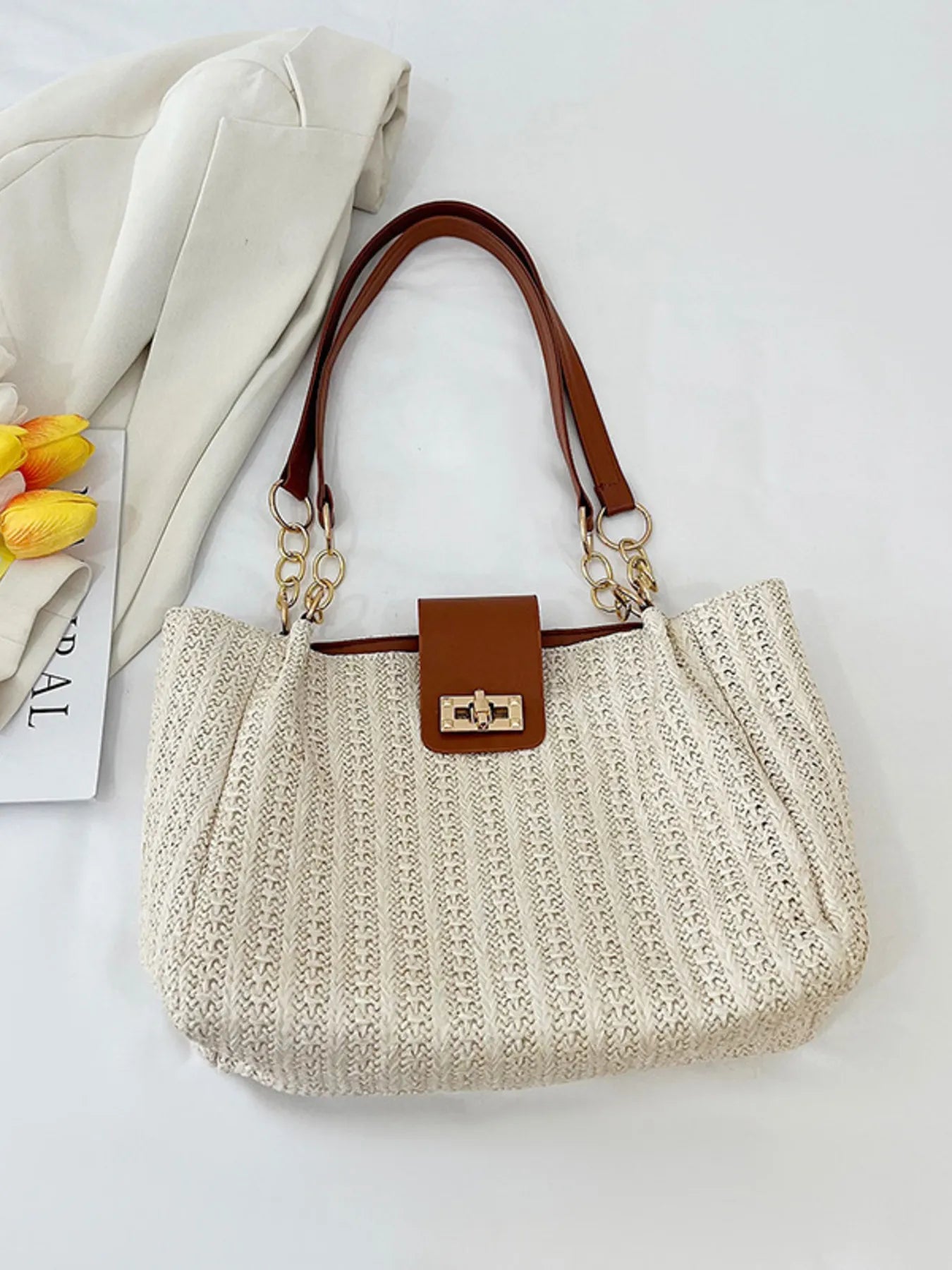 Beige woven handbag with brown handle and trim on a light background