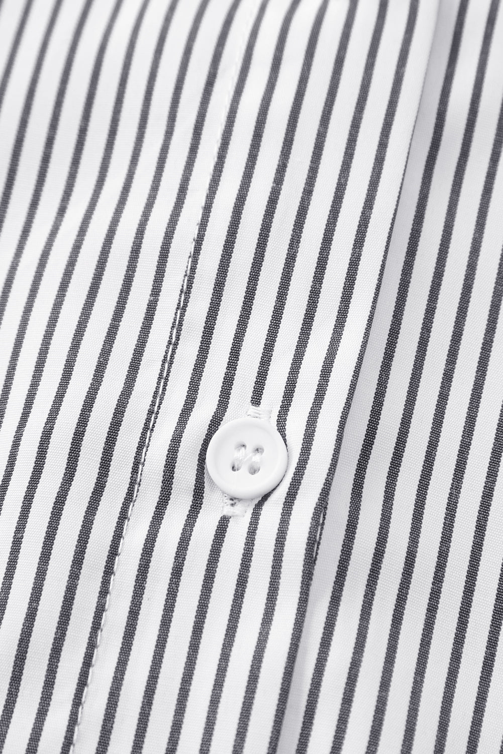 Close-up of a button on a striped shirt with black and white vertical lines.