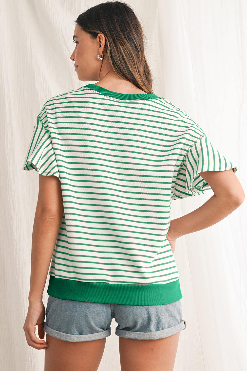 Woman wearing a green and white striped shirt with a plain background
