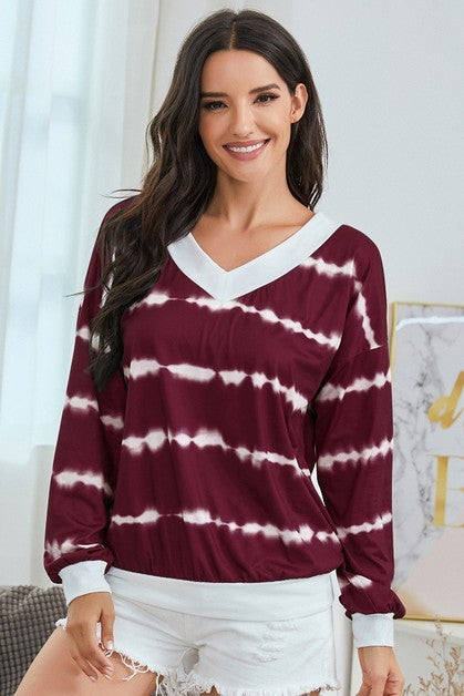 Woman wearing a maroon and white tie-dye sweater with a blurred indoor background