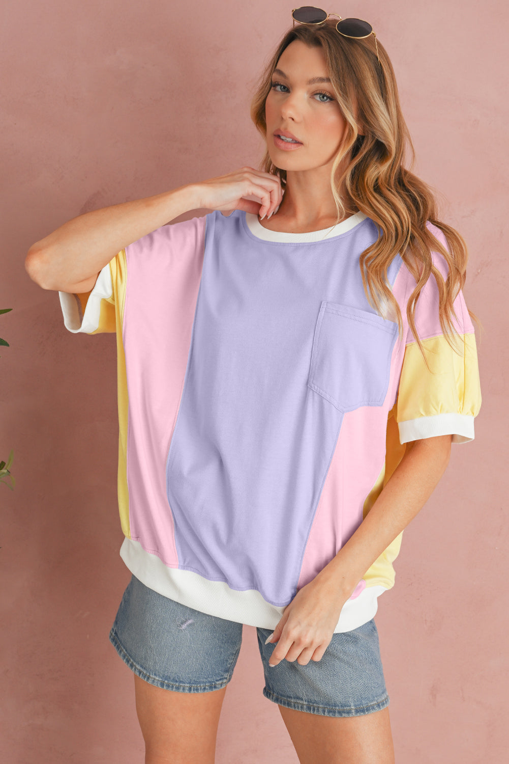 Woman wearing a colorful striped shirt and denim shorts against a pink background