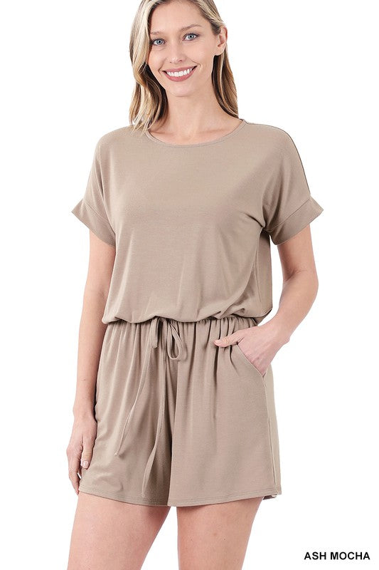 Woman wearing a beige romper with a plain background