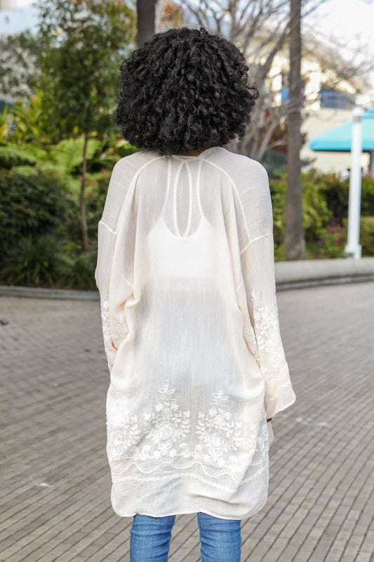Person wearing a white lace kimono-style garment outdoors on a paved path.