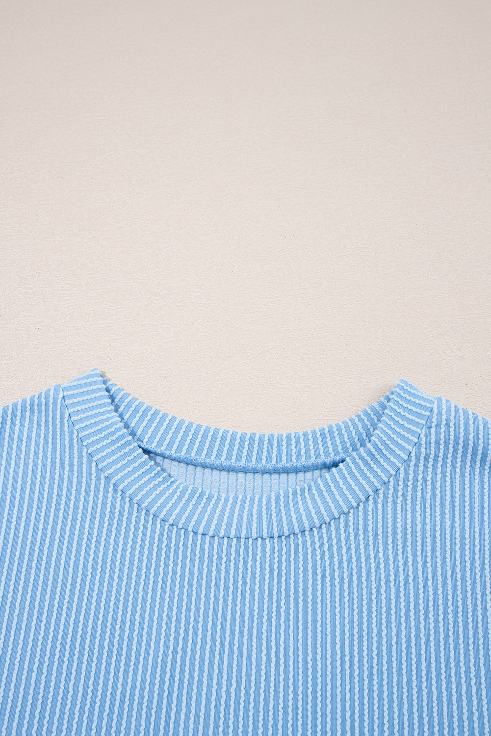 Close-up of a blue striped shirt collar on a beige background