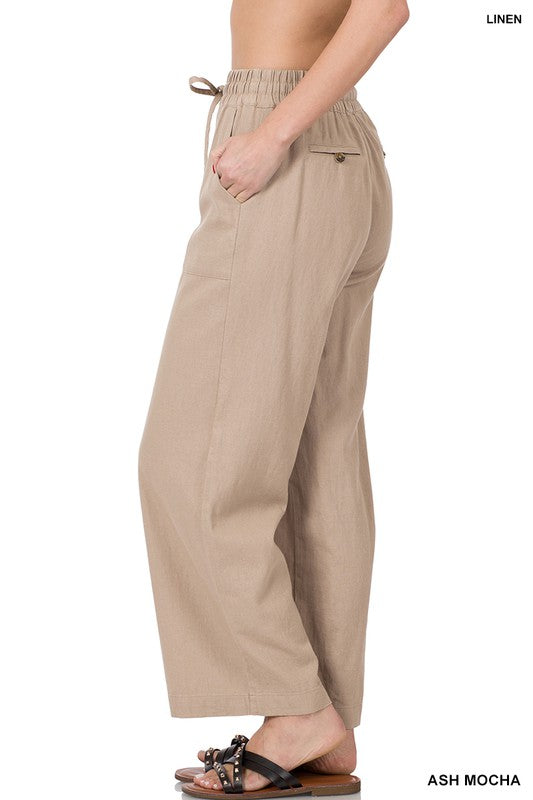 Beige linen pants worn by a person on a white background