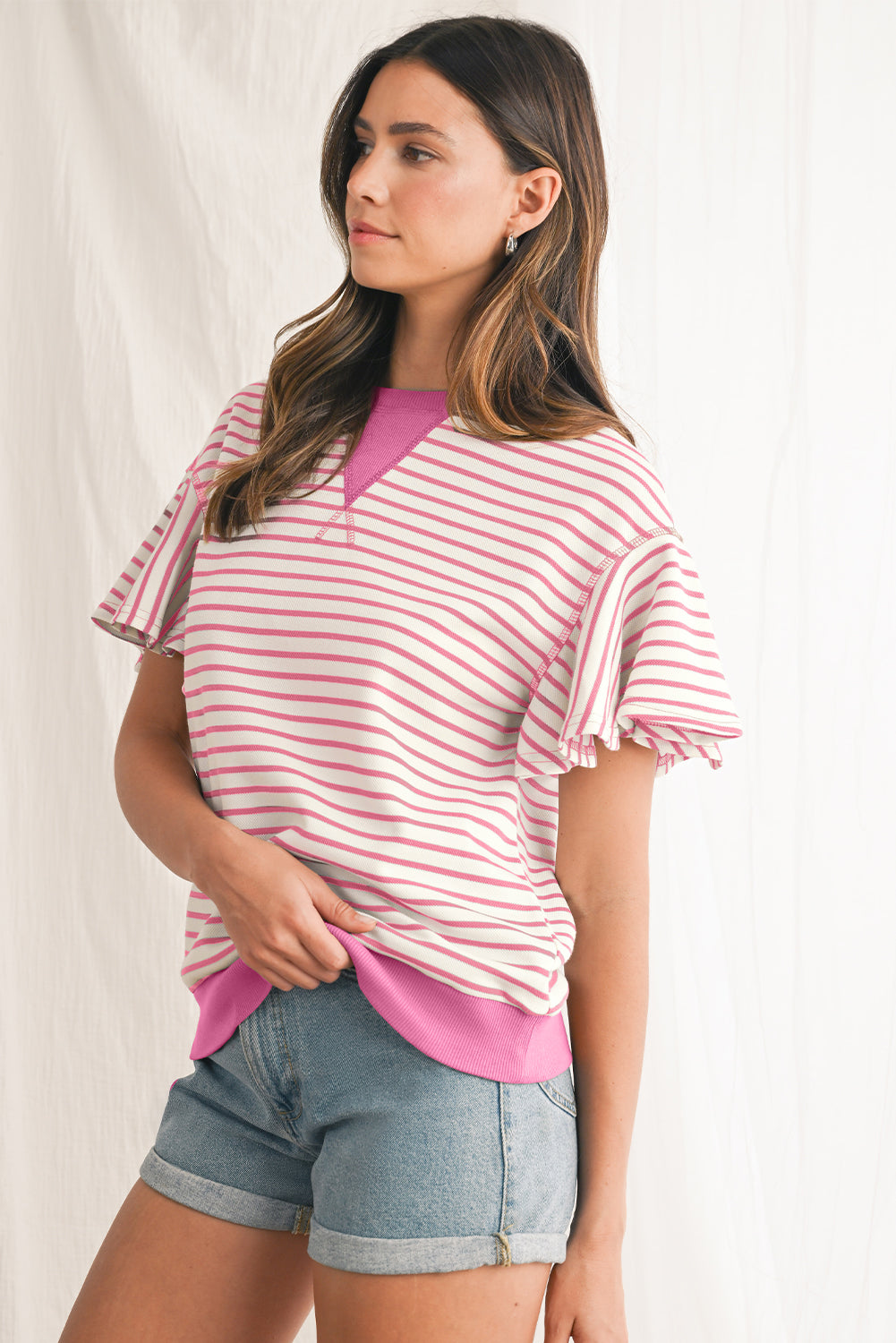 Woman wearing a pink and white striped top with a plain background