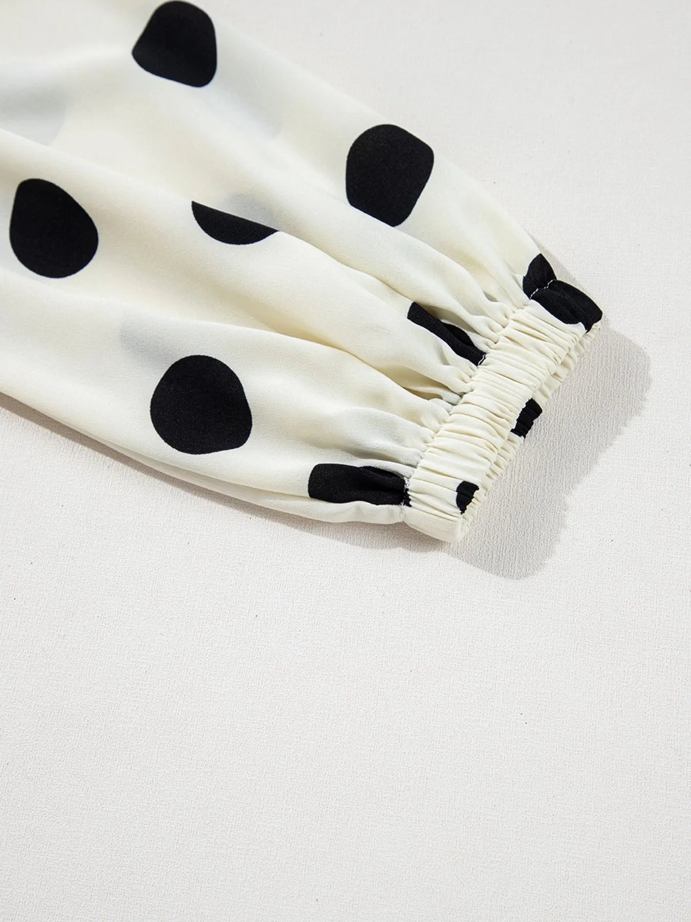 White fabric with black polka dots on a light gray background
