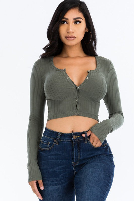 Woman wearing a green ribbed crop top and blue jeans on a white background