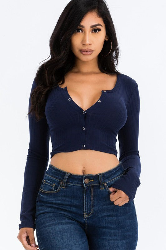 Woman wearing a navy long-sleeve crop top and blue jeans on a white background