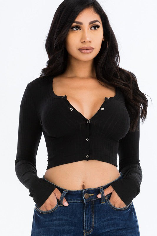 Woman wearing a black long-sleeve crop top and blue jeans on a white background