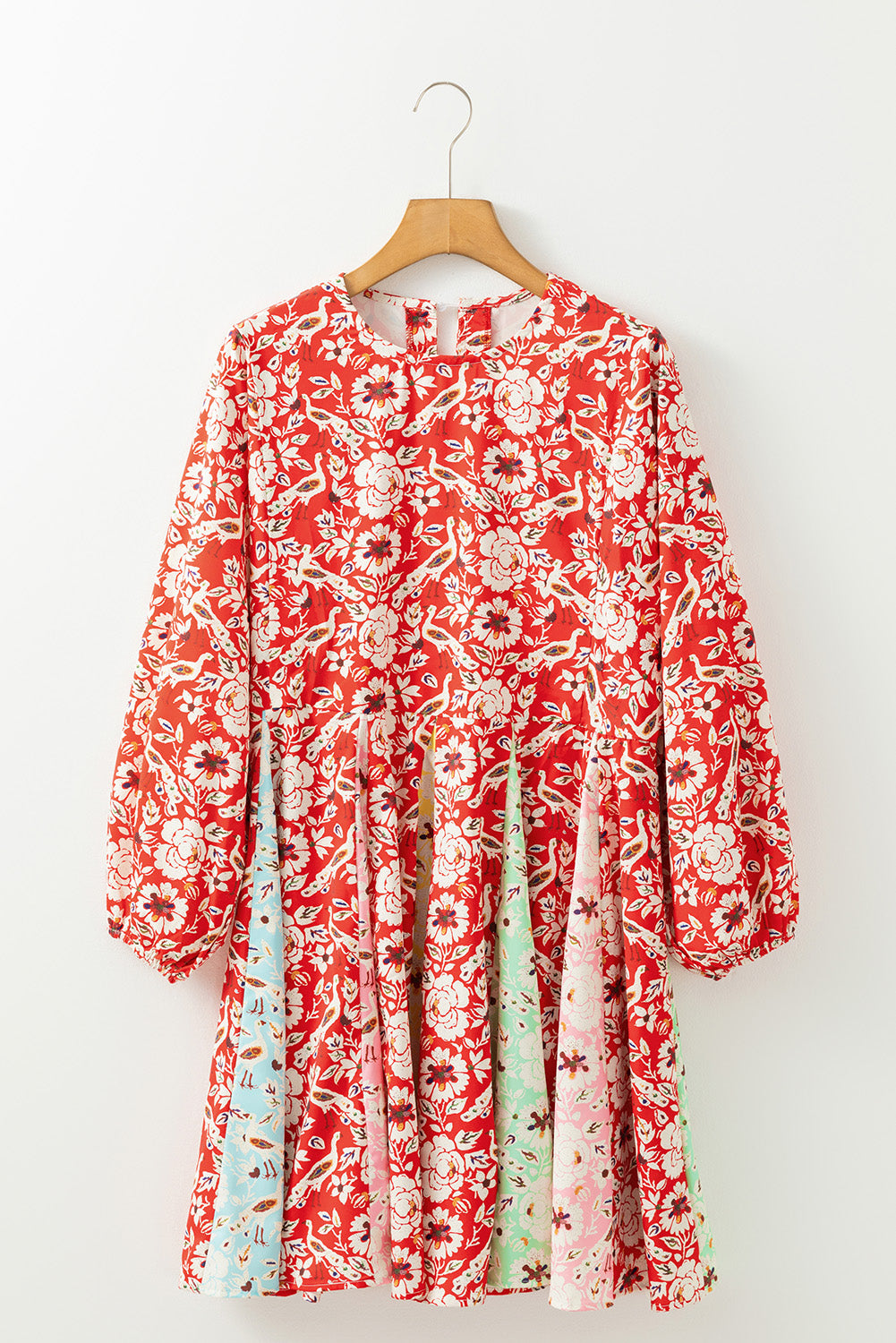 Red floral dress with long sleeves on a wooden hanger against a white background