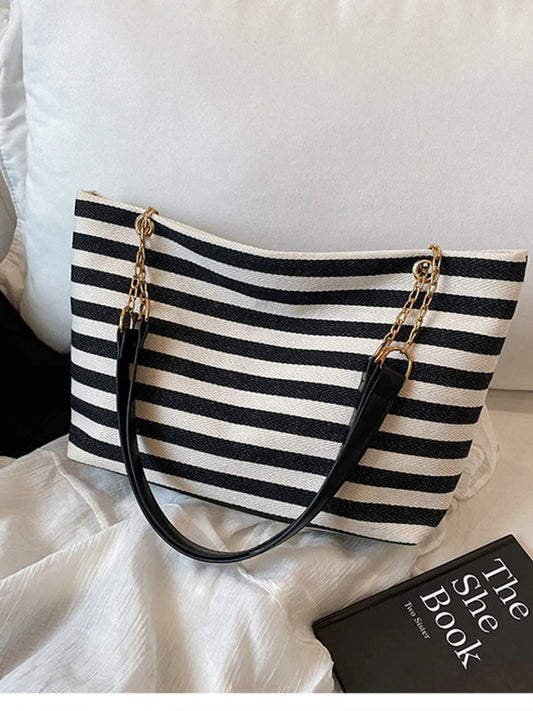 Black and white striped handbag with gold chain on a white surface