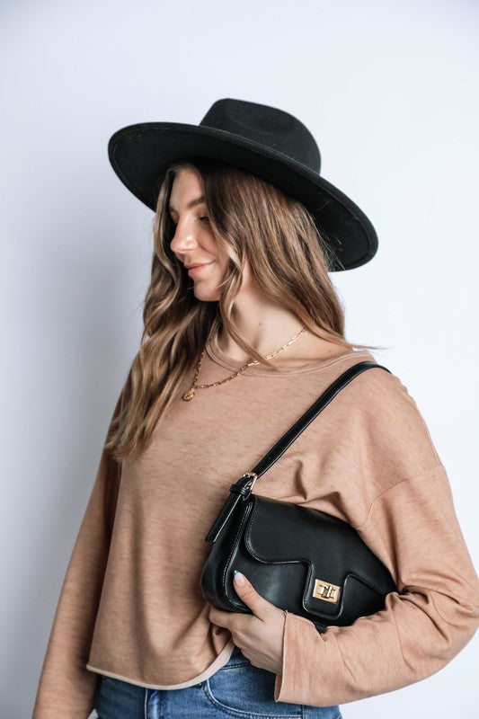 Woman wearing a black hat and holding a black handbag against a white background