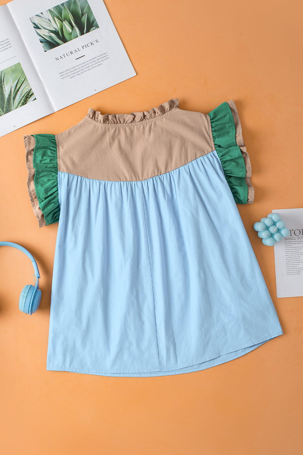Blue and beige dress with green ruffles on an orange background