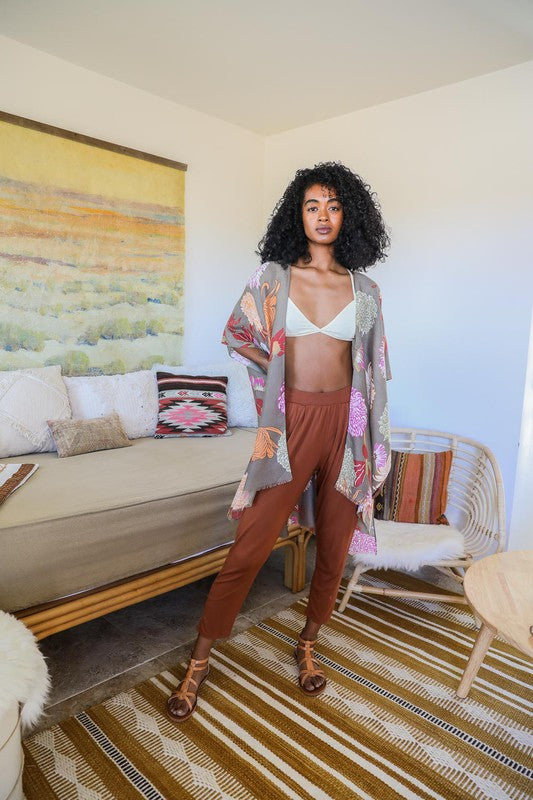 Woman in a stylish outfit standing in a living room with a couch and colorful rug.