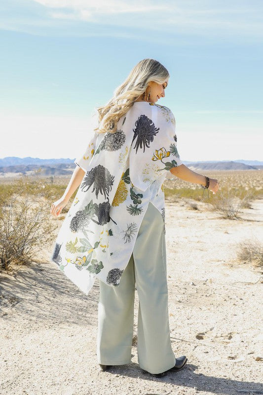 Woman in a desert landscape wearing a floral kimono-style garment.