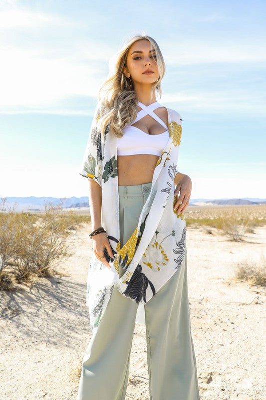 Woman in a desert setting wearing a white top and floral kimono.