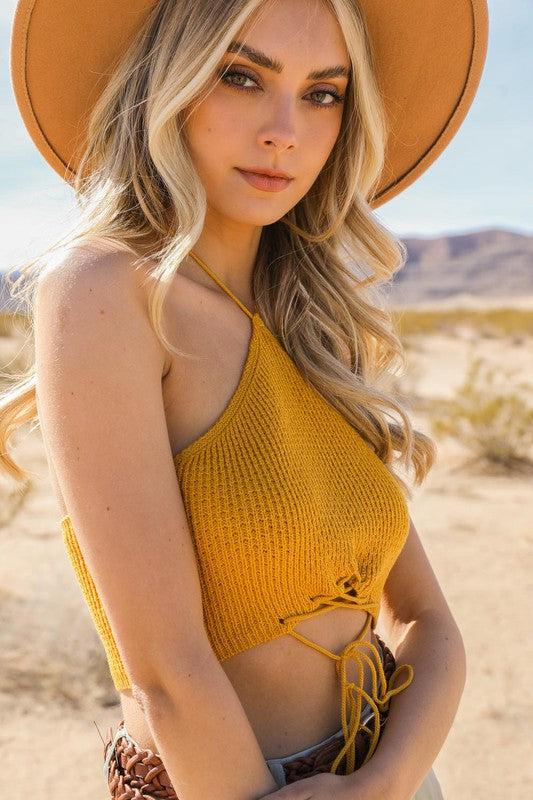 Woman in a yellow top and wide-brimmed hat standing in a desert landscape