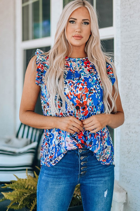 Woman wearing a colorful floral top and blue jeans standing outdoors.