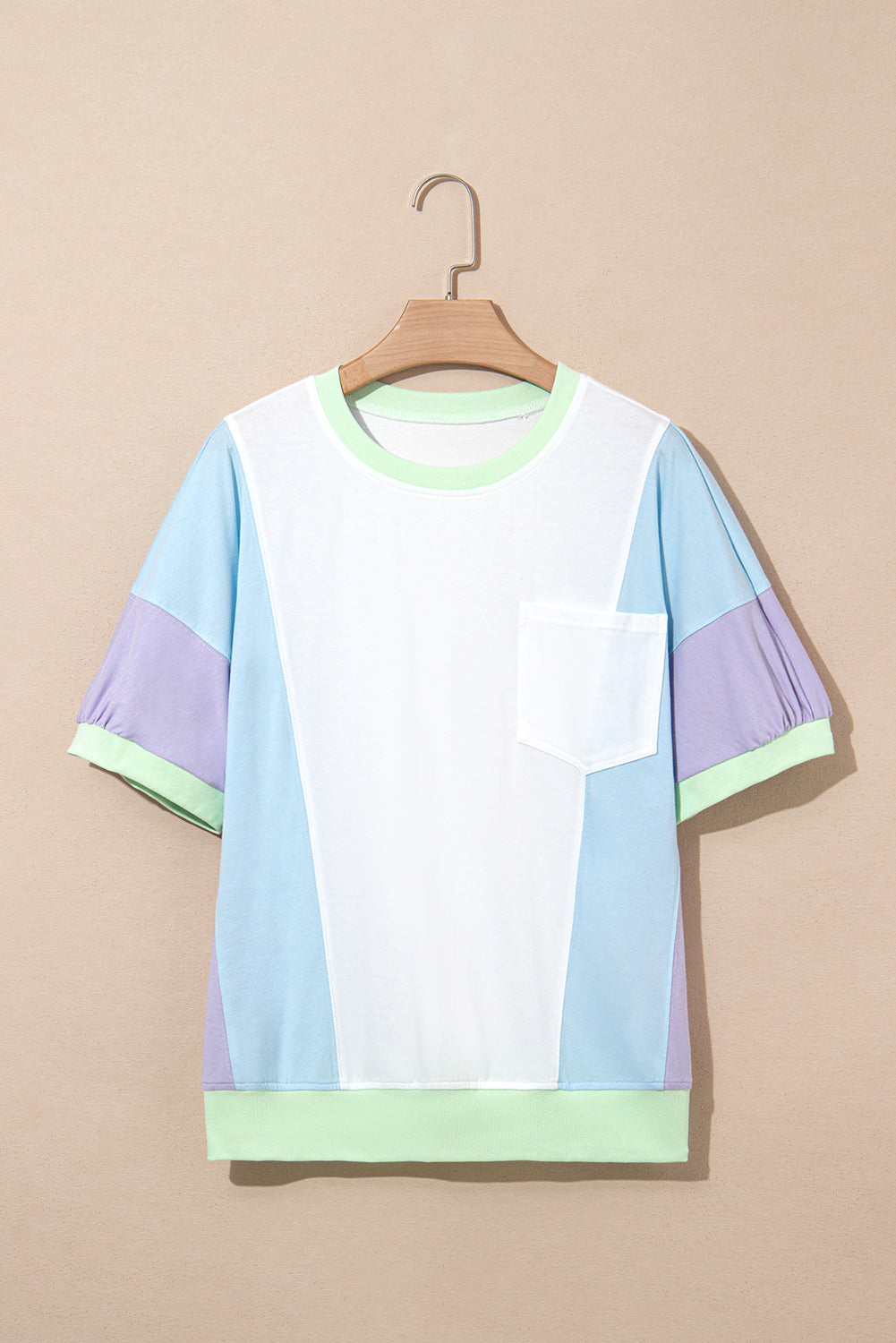 Color-blocked t-shirt on a hanger against a beige background