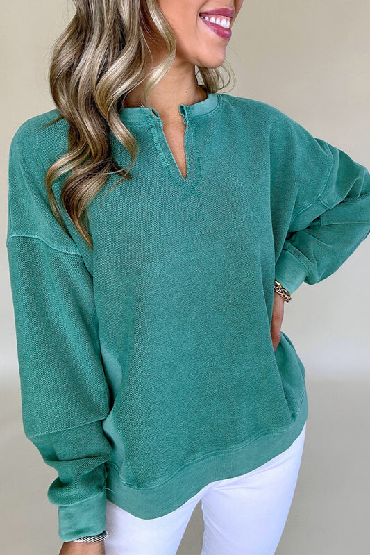 Person wearing a teal sweatshirt with a plain background
