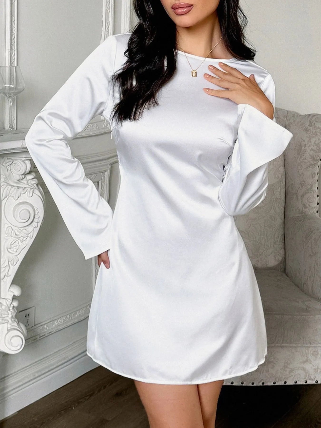 Woman wearing a white dress with long sleeves in an indoor setting.