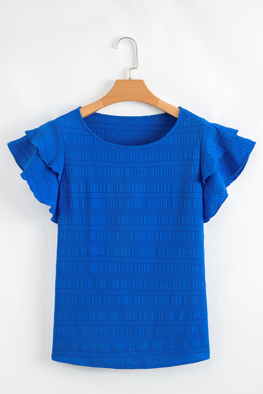 Blue top with ruffled sleeves on a wooden hanger against a white background