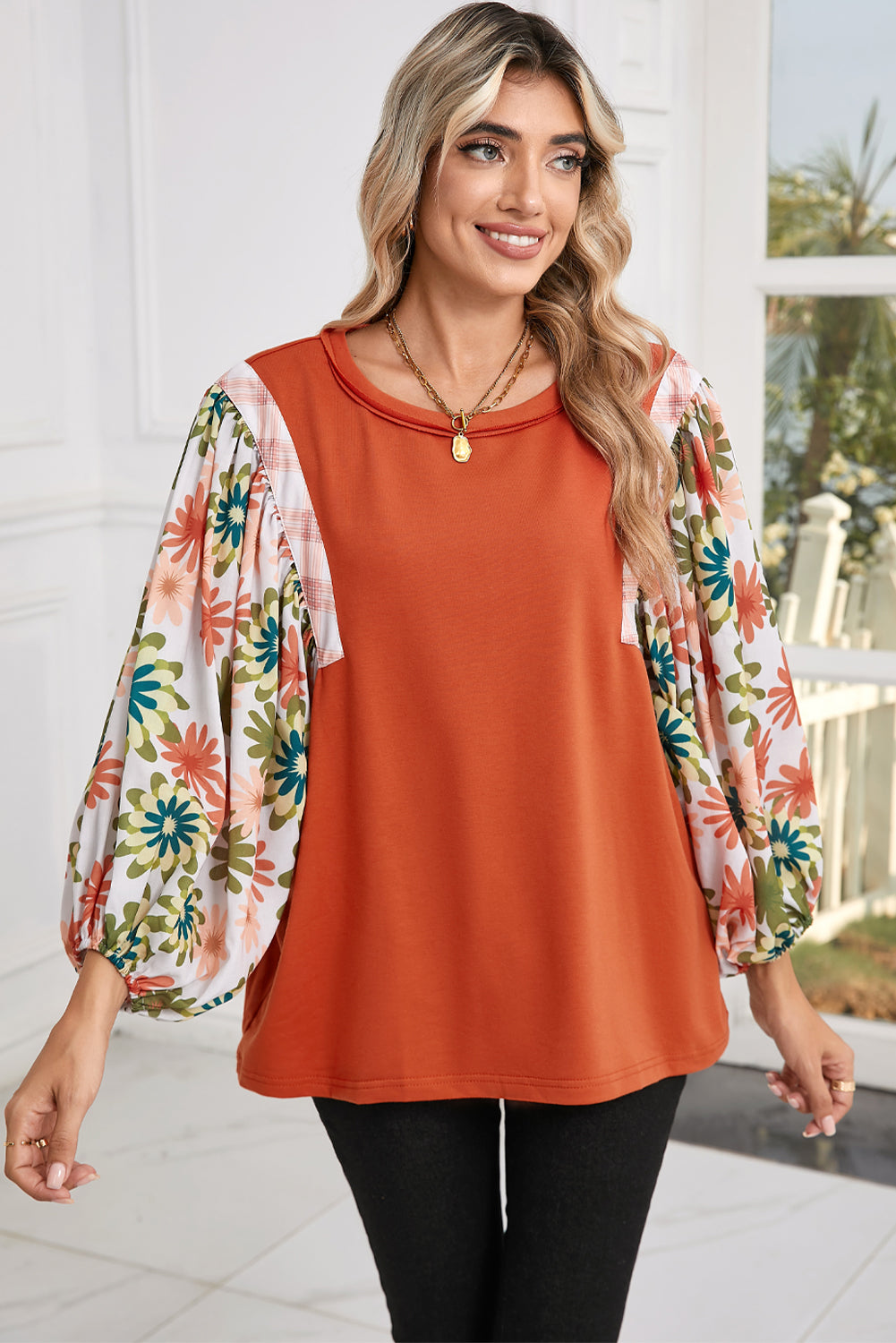 Woman wearing an orange top with floral sleeves outdoors