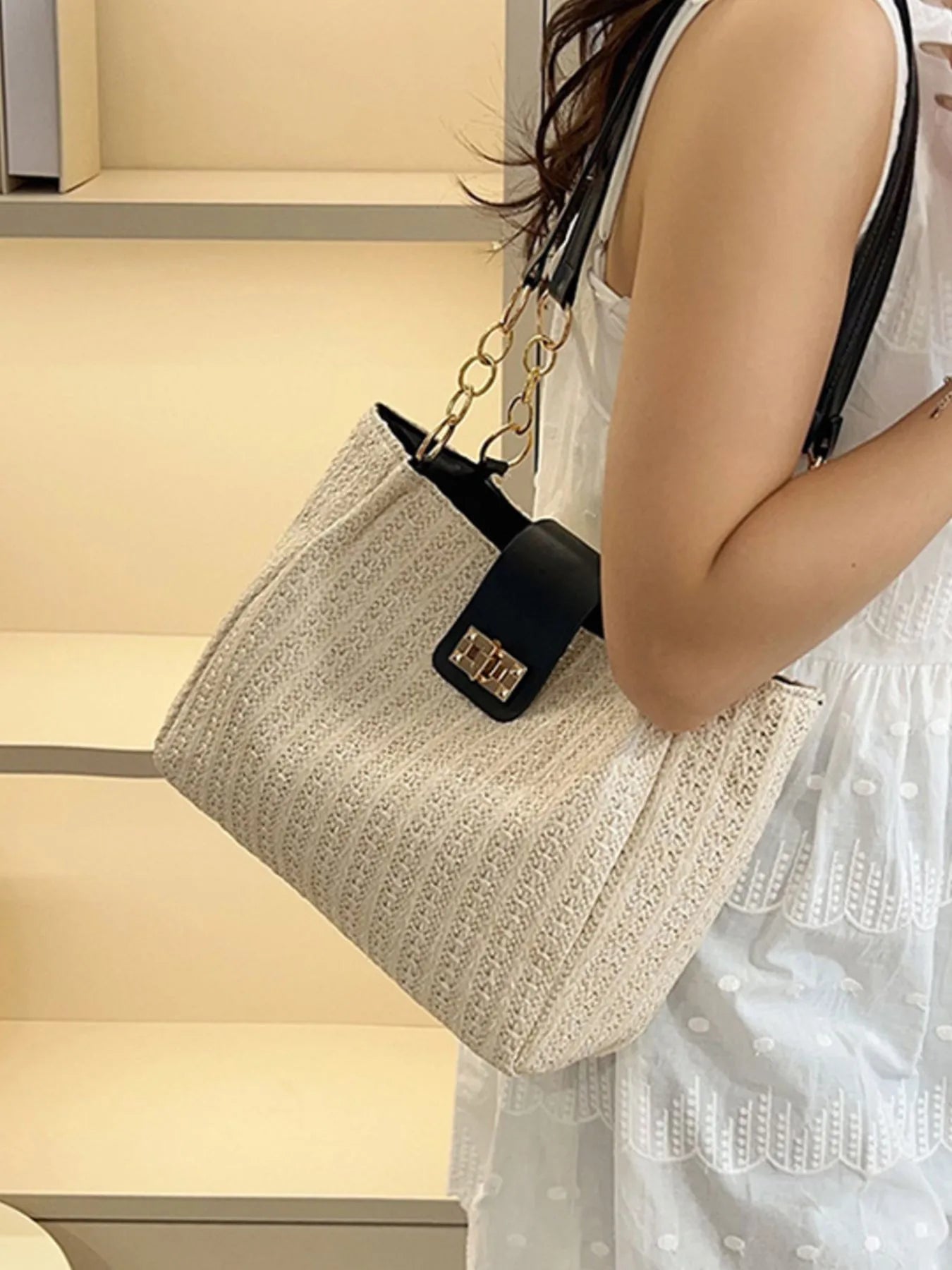 Person holding a textured handbag with a neutral background